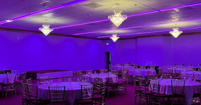 Elegant banquet room with round tables and purple lighting for weddings and corporate events.