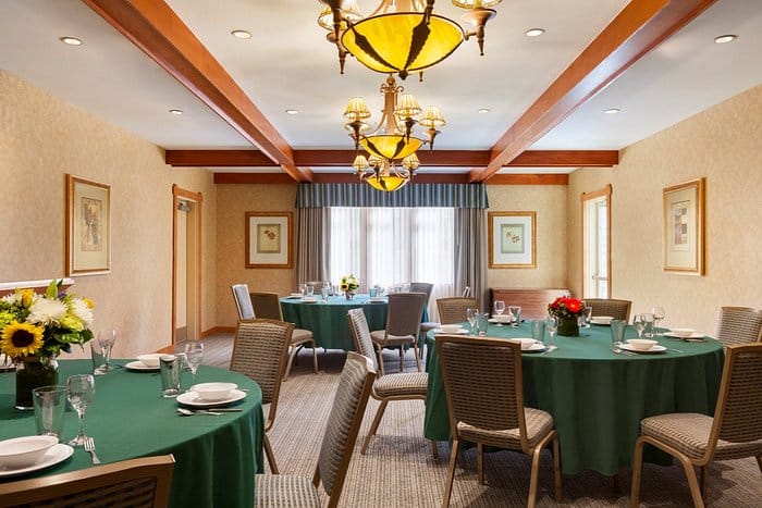 Meeting room with round tables and chandeliers at Homewood Suites, ideal for events.