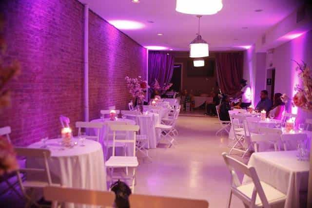 Elegant event space in Brooklyn with round tables and soft purple lighting for gatherings.