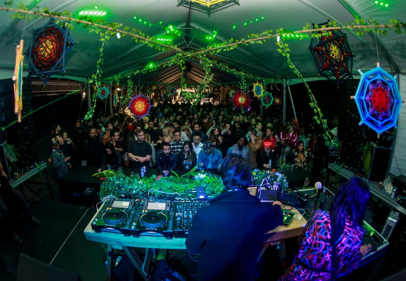 Vibrant Block Party in The Midway with DJ, colorful lights, and lush greenery.