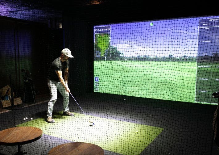 Golfer in high-tech indoor simulator at Silver Star Social Club for corporate events.