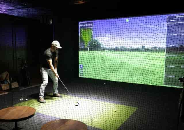 Golfer in high-tech indoor simulator at Silver Star Social Club for corporate events.