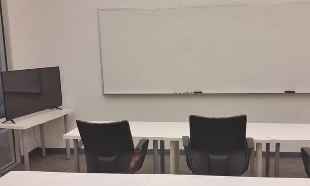 Minimalist conference room with chairs, whiteboard, and TV for professional meetings.
