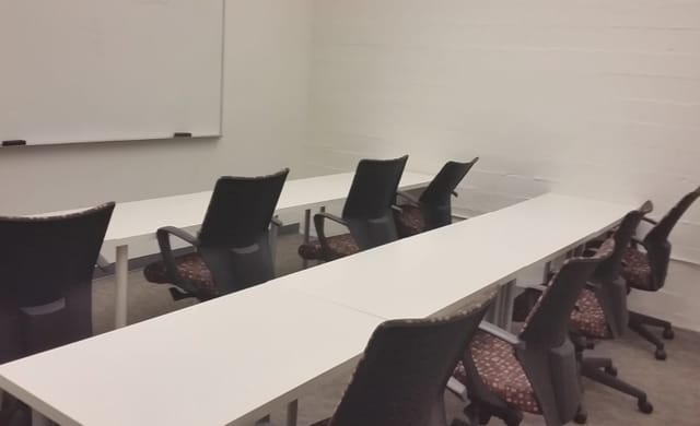 Minimalist conference room with U-shaped tables for workshops and team meetings.