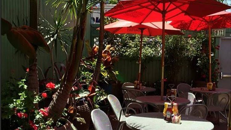 Heated patio at Mars Bar & Restaurant with red umbrellas for casual social events.