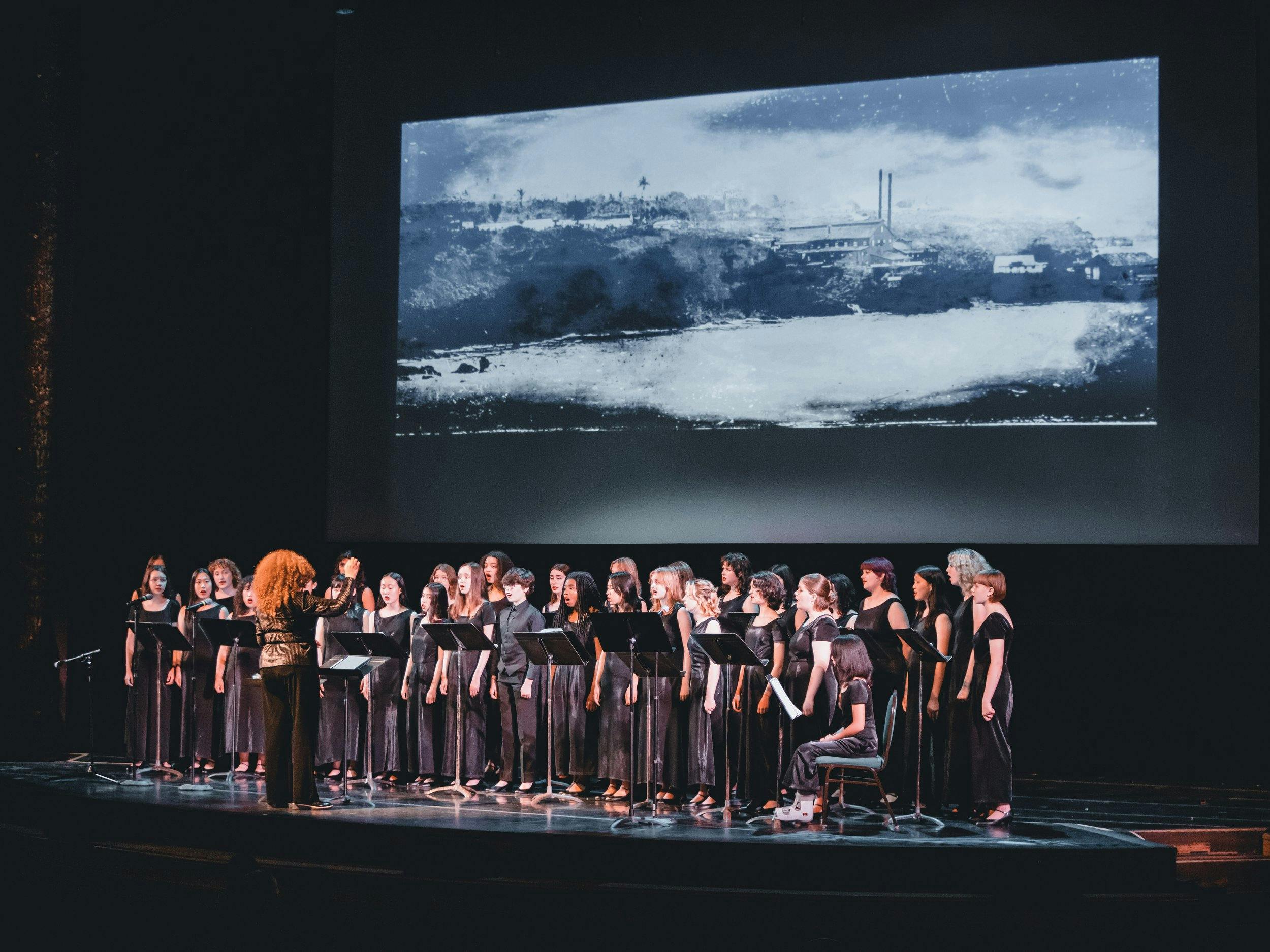 Choir performing on stage in Noe Music concert hall with striking backdrop.