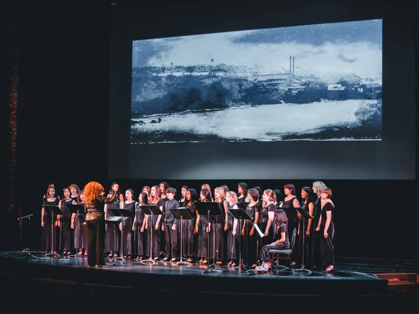 Choir performing on stage in Noe Music concert hall with striking backdrop.