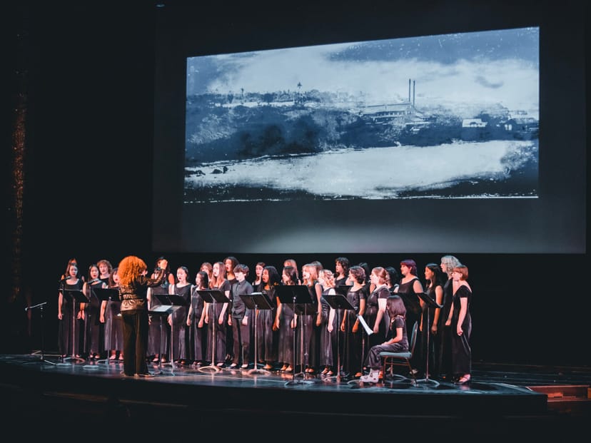 Choir performing on stage in Noe Music concert hall with striking backdrop.