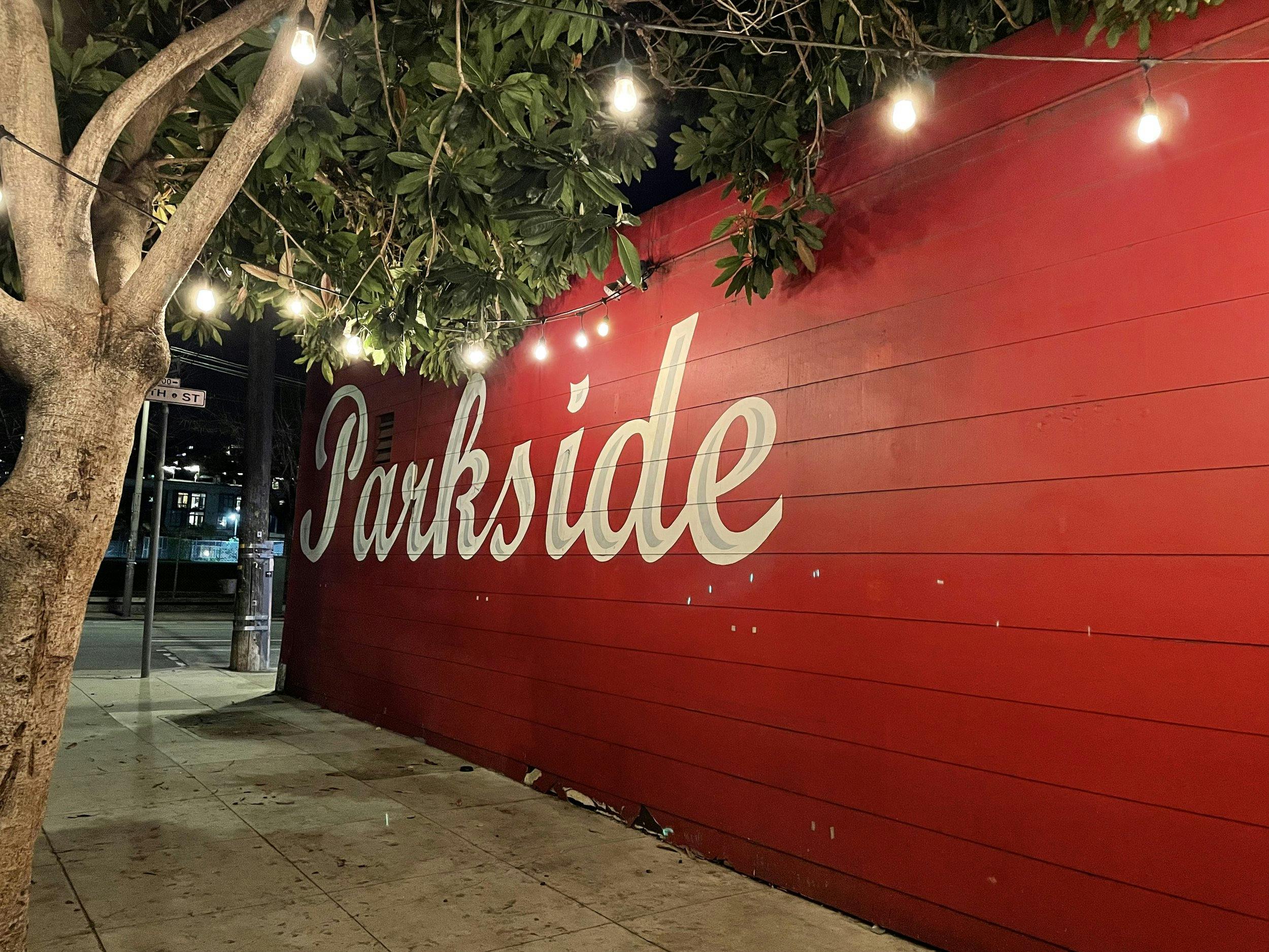 Outdoor networking event at Coffee in Thee Parkside with vibrant red wall and string lights.