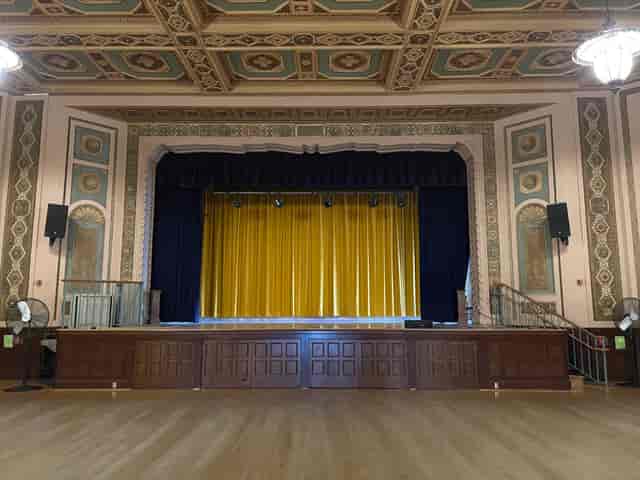 Spacious Lake Merritt Dance Hall 3 with grand stage and vibrant yellow curtain for events.