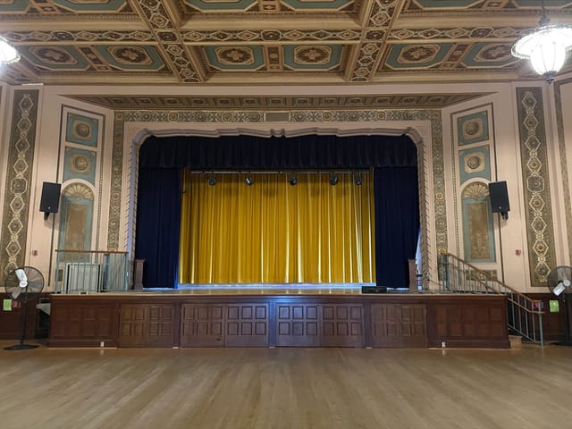 Spacious Lake Merritt Dance Hall 3 with grand stage and vibrant yellow curtain for events.