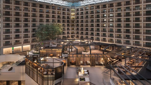 Modern hotel atrium with glass ceiling, ideal for conferences and social events.