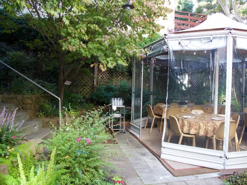 Charming tented outdoor event space with elegant tables in Ragazza's lush greenery.