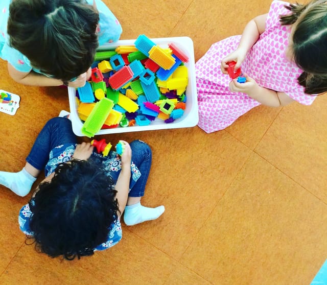Children playing with colorful building blocks in a vibrant STEM education center.