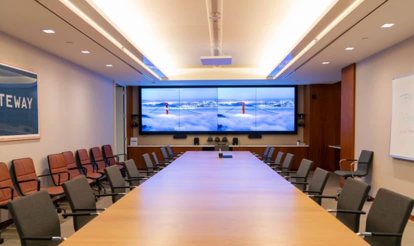 Modern conference room with sleek table and dual screens for corporate meetings.