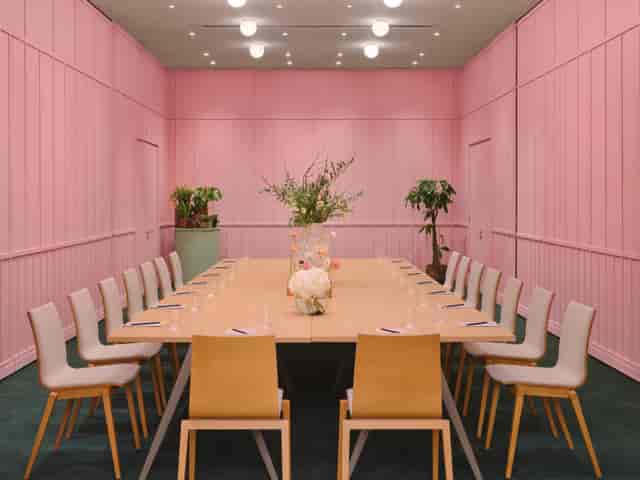 Stylish meeting room with pink backdrop, ideal for creative sessions and formal meetings.