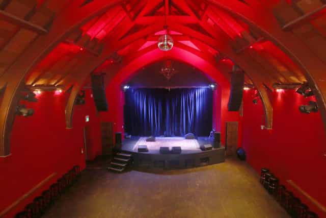 Vibrant red event space with raised stage, ideal for concerts and corporate events.