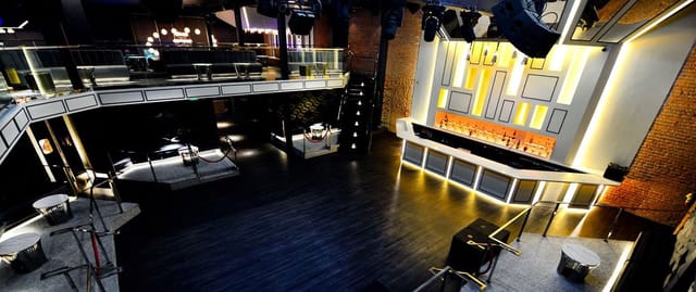 Versatile event space with sleek bar, ideal for corporate gatherings and social events.