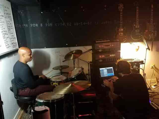 Dynamic rehearsal room with drummer and sound engineer for live event production.