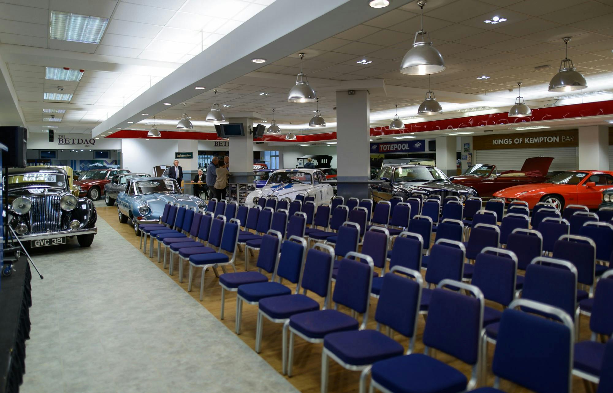 Exhibition Hall at Kempton Park: spacious venue with blue chairs and vintage cars for events.