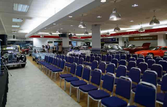 Exhibition Hall at Kempton Park: spacious venue with blue chairs and vintage cars for events.