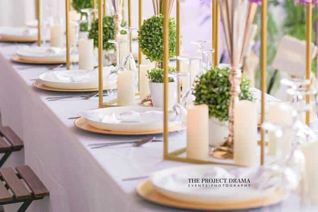 Elegant dining table with greenery and candles for weddings or corporate events.