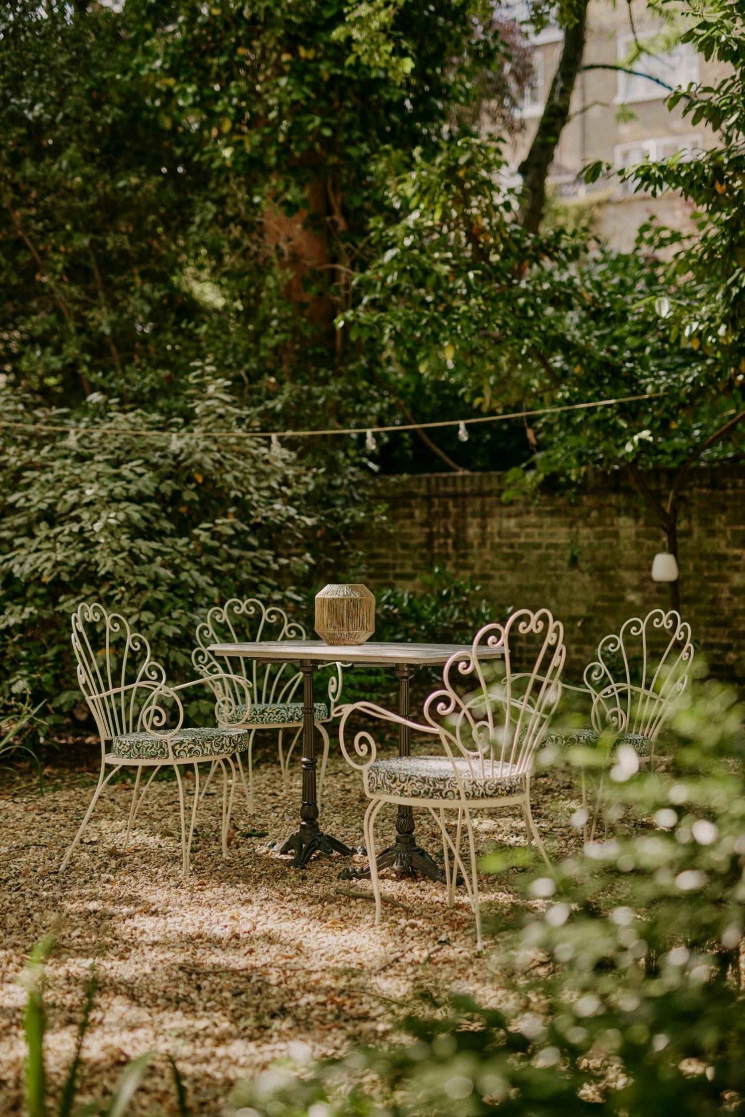 Charming EVE Kensington garden with wrought-iron furniture for events and gatherings.