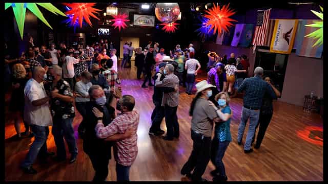 Lively dance event in Sundance Saloon's Main Ballroom with vibrant decor and disco balls.