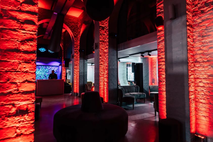 Stylish event space at The Vaults, One Marylebone with exposed brick and red lighting.