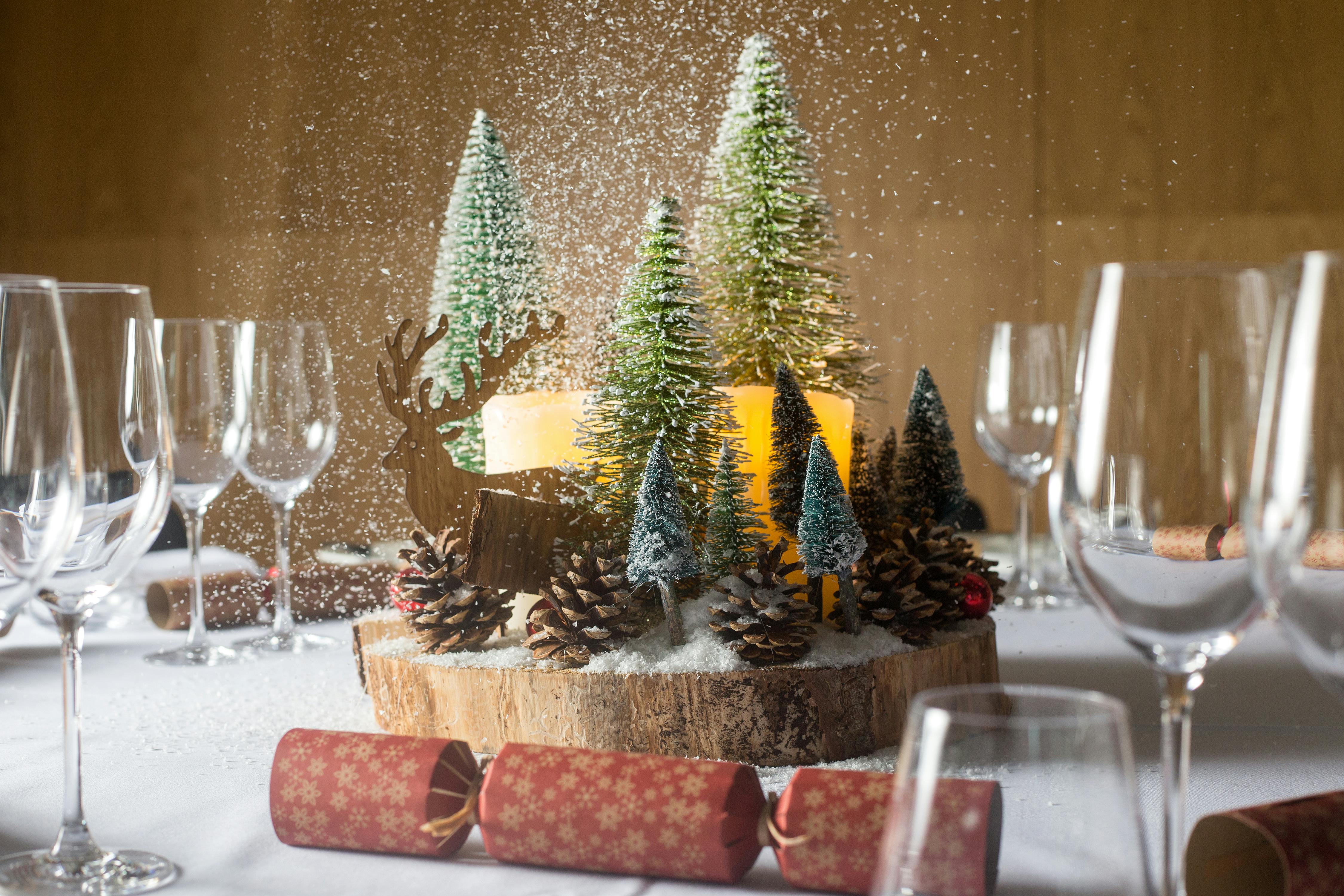 Christmas party table centerpiece with evergreen trees and elegant glassware.