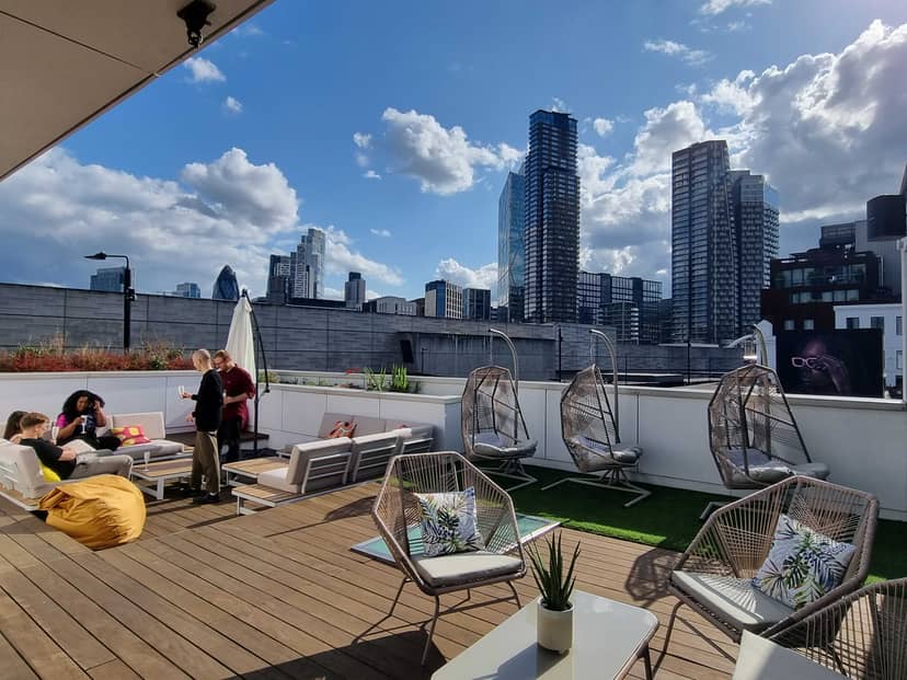 Stylish rooftop event space with modern furniture and city backdrop for gatherings.