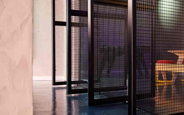 Modern industrial meeting space with wire mesh partitions for collaborative sessions.