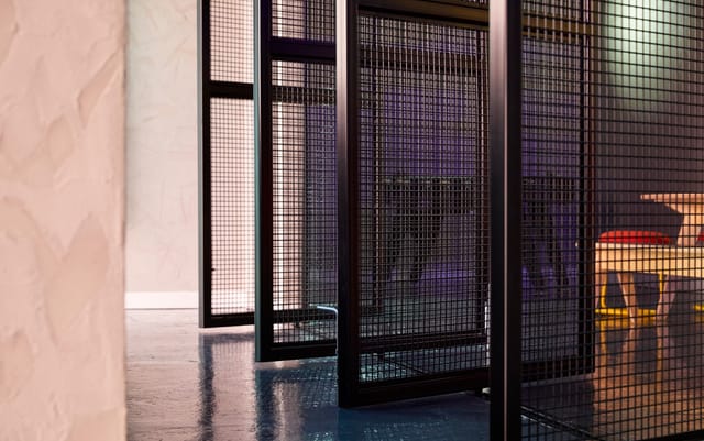 Modern industrial meeting space with wire mesh partitions for collaborative sessions.