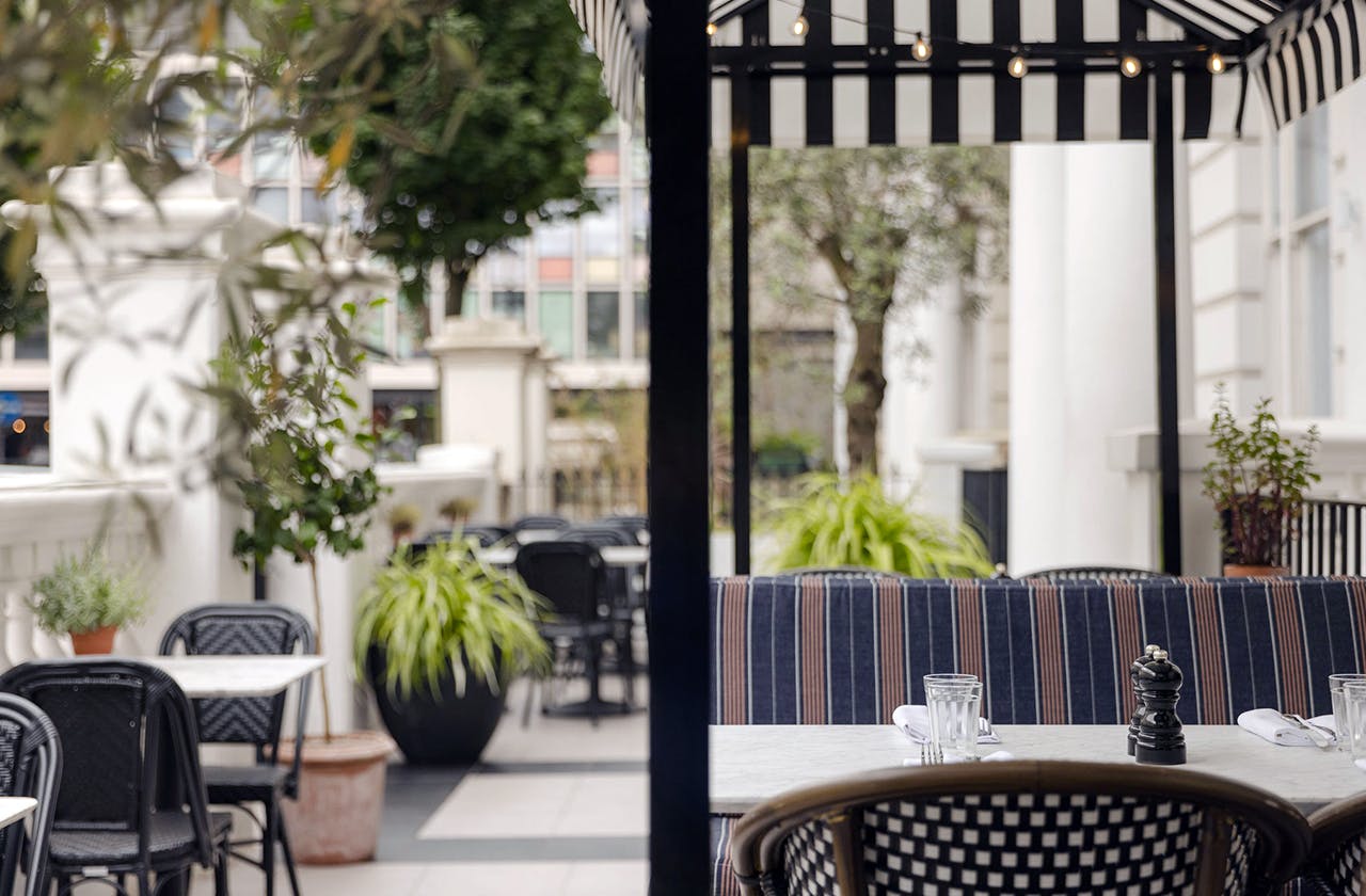 Charming outdoor dining area at The Laslett with striped awning for events and gatherings.