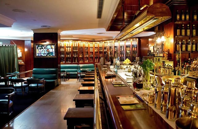 Sophisticated speakeasy bar with warm wood tones, ideal for cocktail receptions and networking.