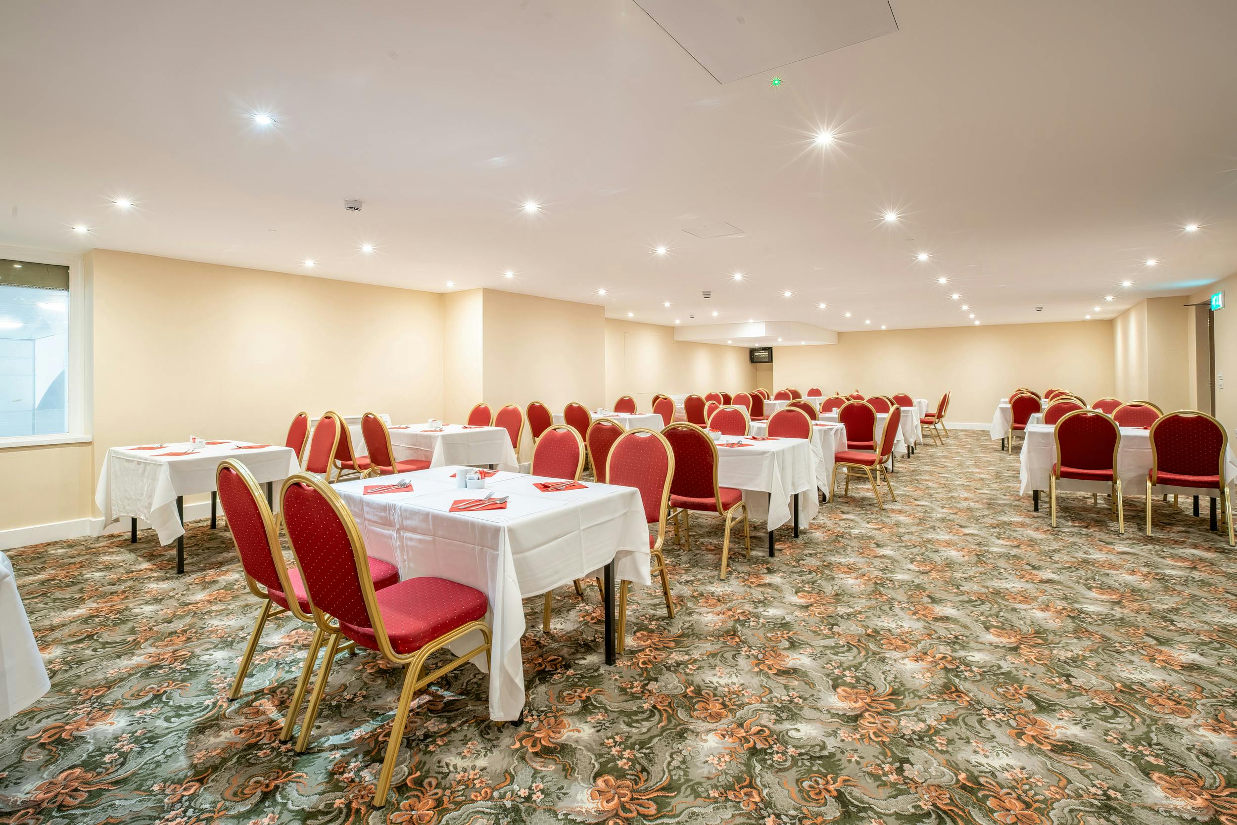 Cambridge Suite at Millennium Gloucester, elegant meeting space with red chairs.