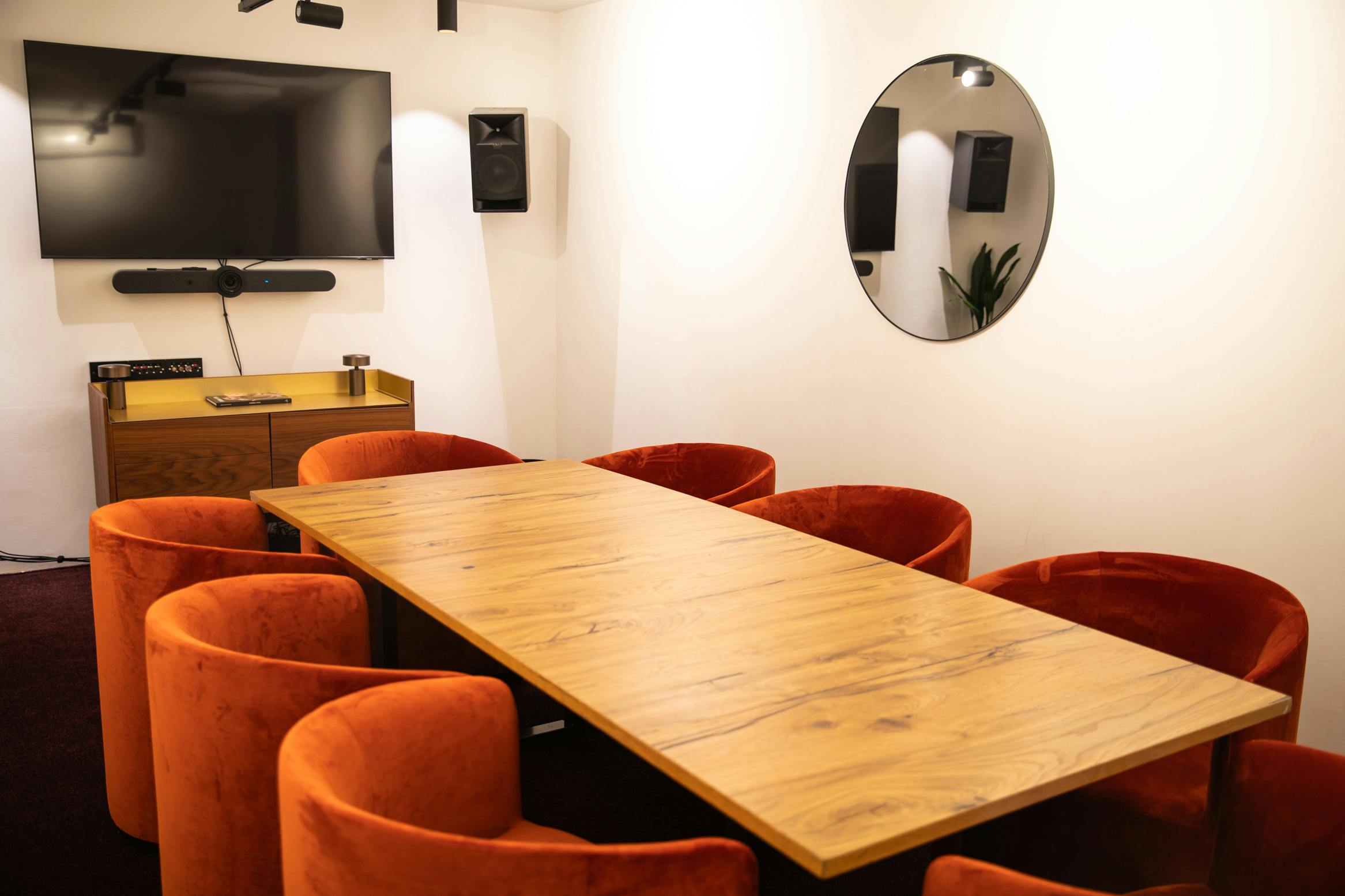 Modern meeting room with wooden table and orange chairs for collaboration and brainstorming.