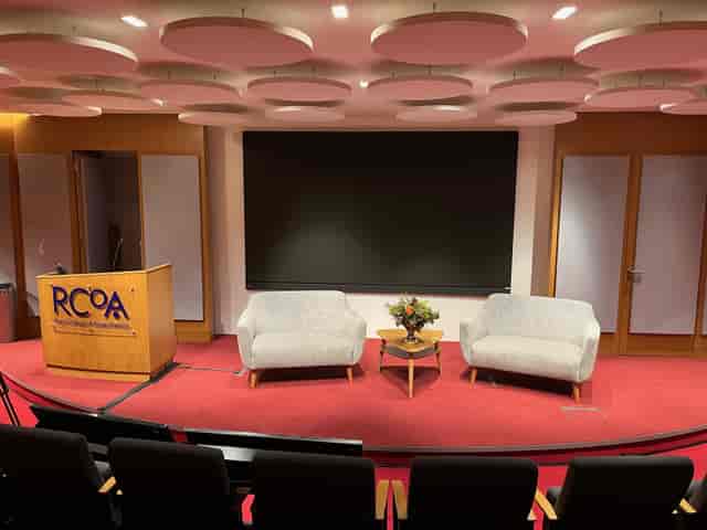 Lecture theatre stage with branded lectern and lounge seating for corporate event panel discussions.