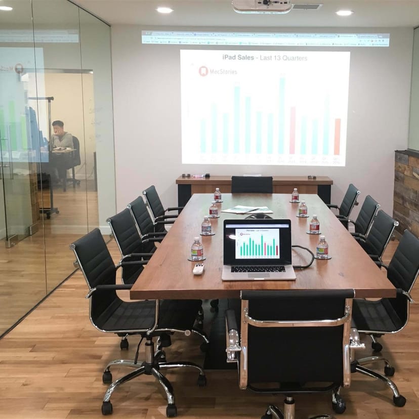 Modern conference room with projector for iPad sales meeting, featuring large table and chairs.