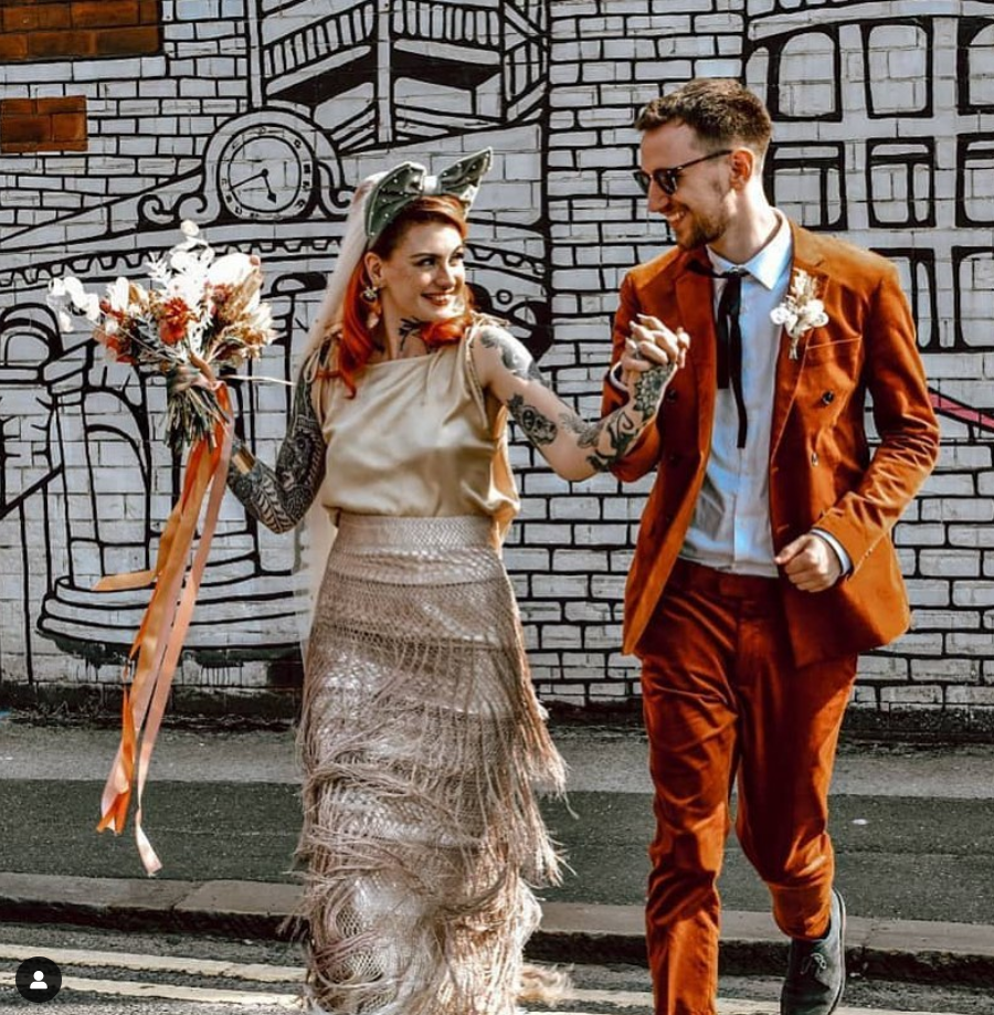 Stylish couple celebrating modern wedding against vibrant mural backdrop in The Furnace. - Banner