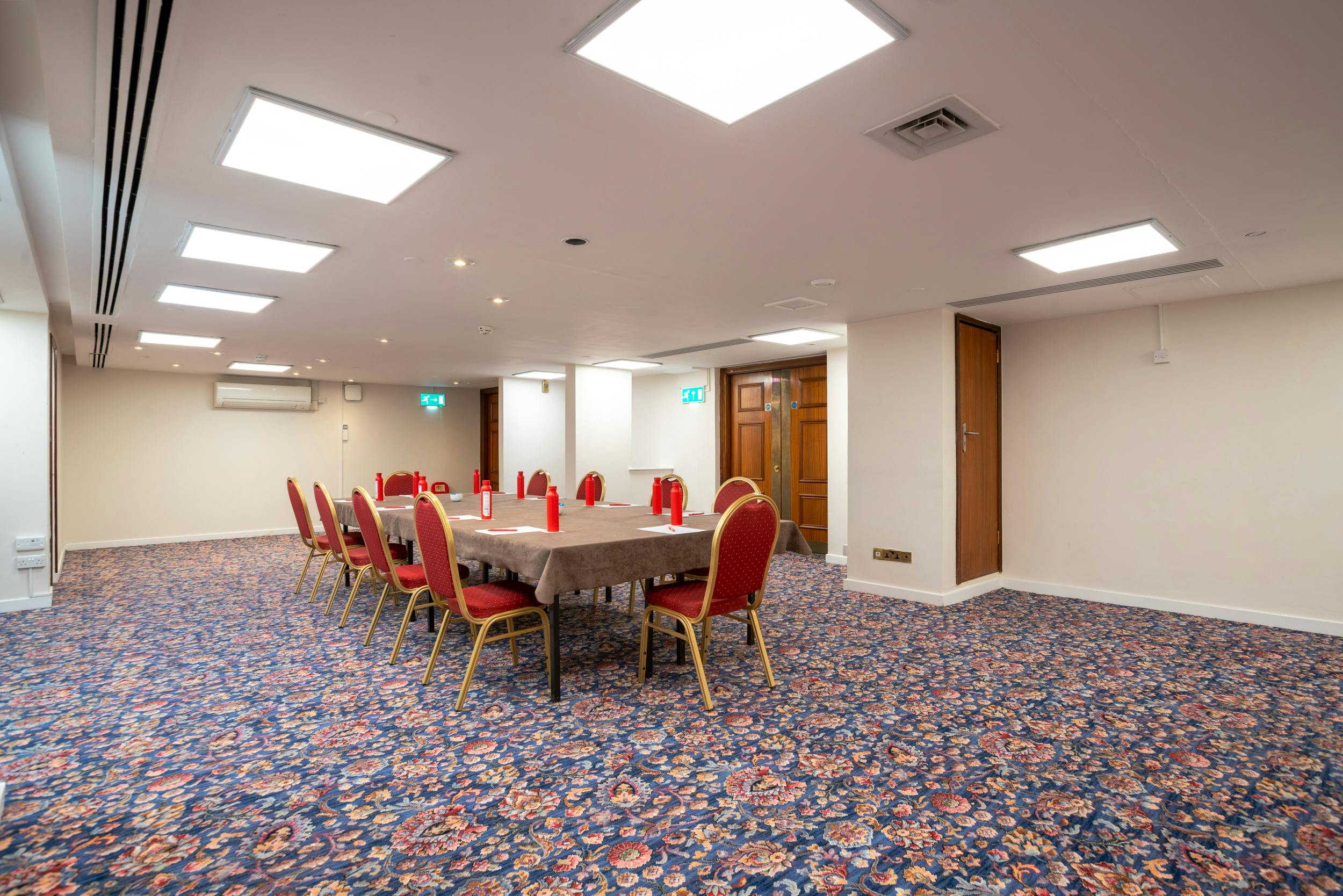 Cromwell 6 meeting room in Kensington with red chairs, perfect for workshops and presentations.