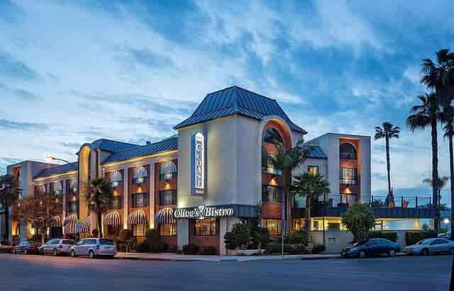 Well-lit Hotel Burbank exterior with palm trees, perfect for meetings and events.
