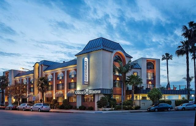Well-lit Hotel Burbank exterior with palm trees, perfect for meetings and events.