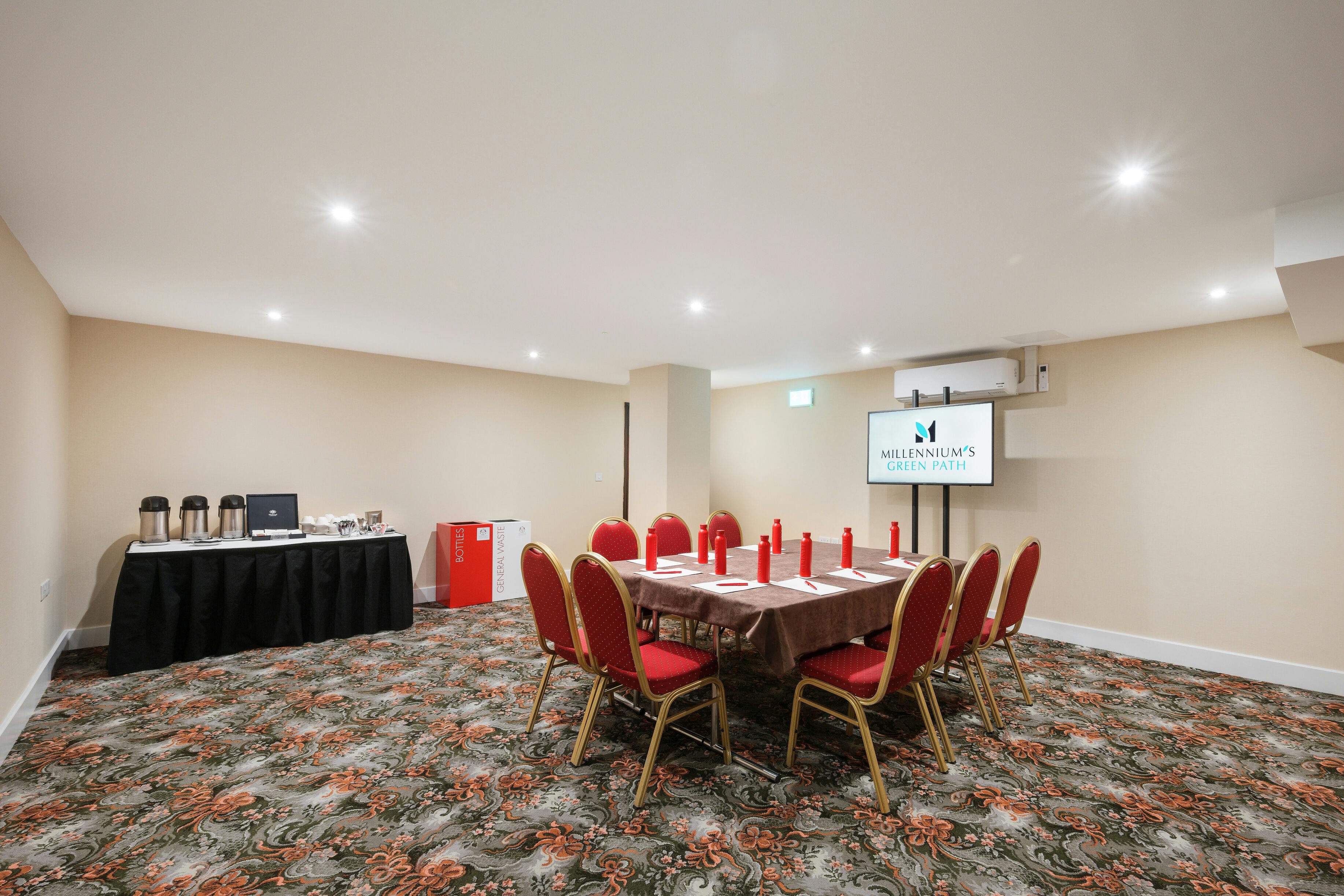 Windsor Suite meeting room with round table and red chairs, perfect for workshops and conferences.