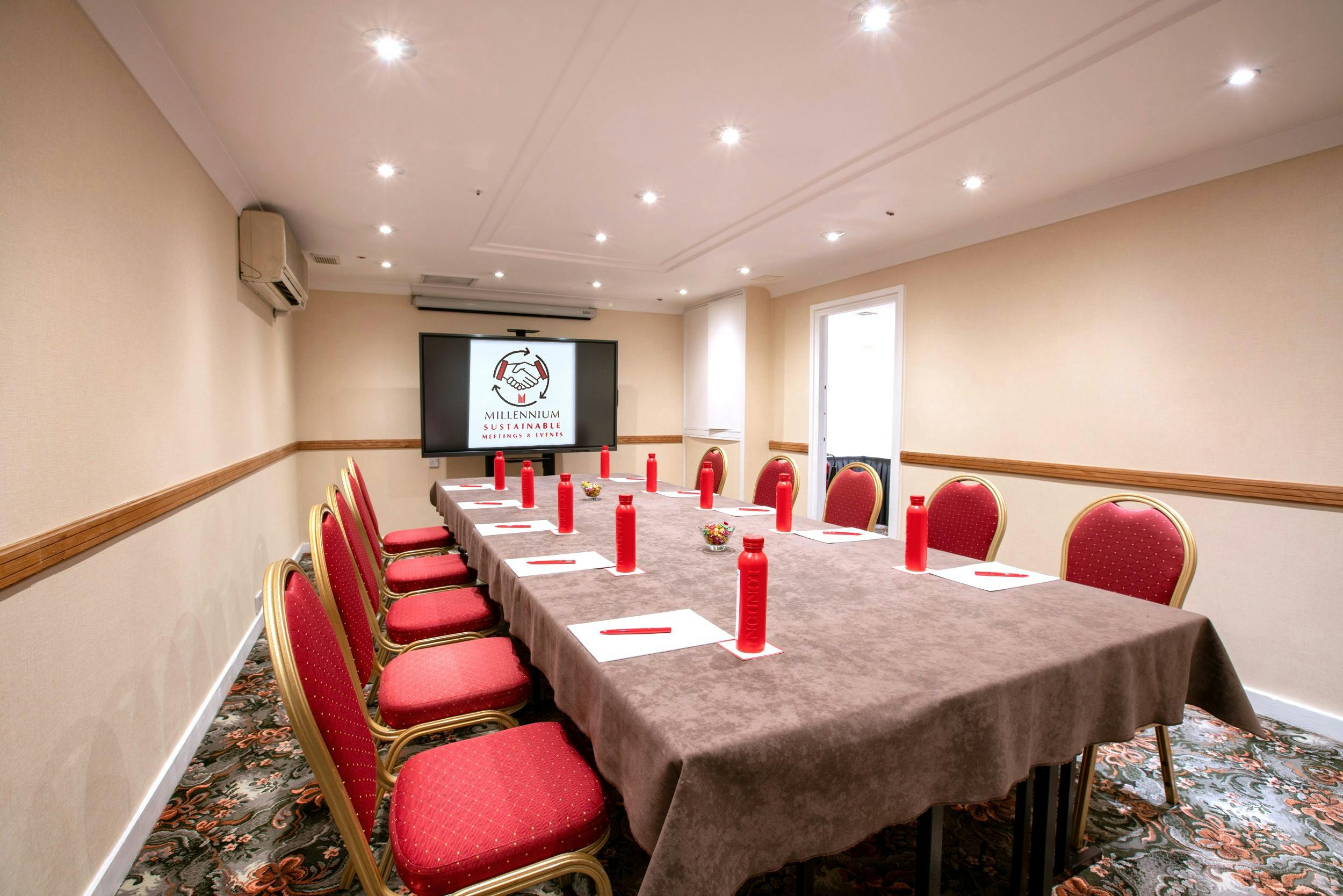 Brompton Boardroom in London with a long table set for formal meetings and red candle centerpieces.