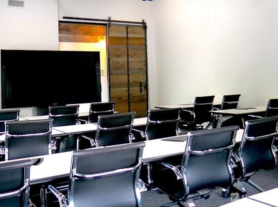 Modern classroom training room with sleek black chairs and presentation screen.