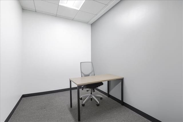 Minimalist meeting room with desk and chair for intimate discussions or brainstorming sessions.