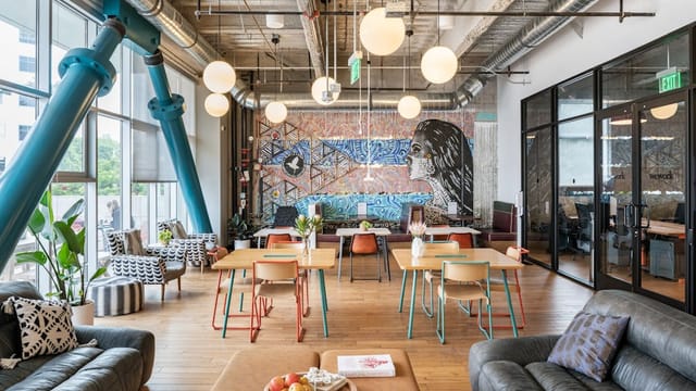 Modern coworking space with vibrant mural, ideal for meetings and events.