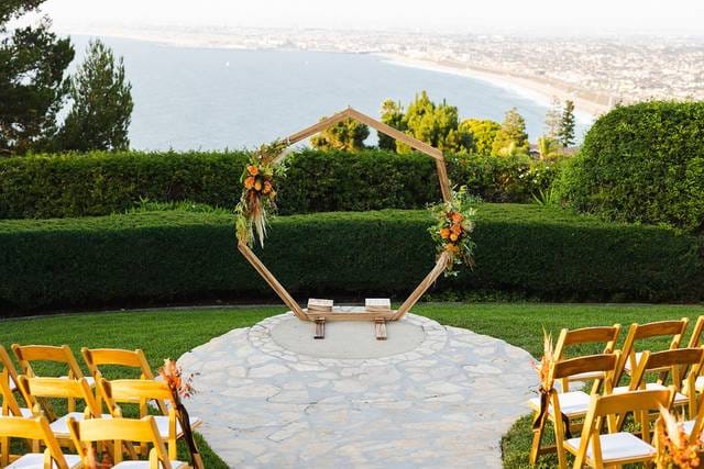 Outdoor wedding ceremony at La Venta Inn with floral arch and ocean backdrop.