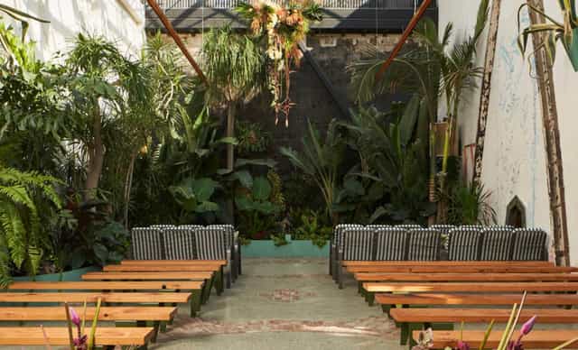 Greenhouse Courtyard in DTLA: serene outdoor event space with wooden benches and lush greenery.
